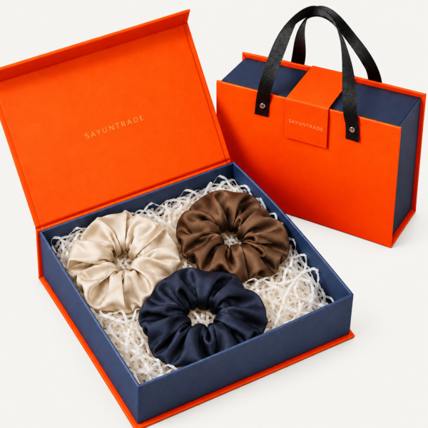 Three large silk scrunchies presented in an orange and navy gift box with matching gift bag